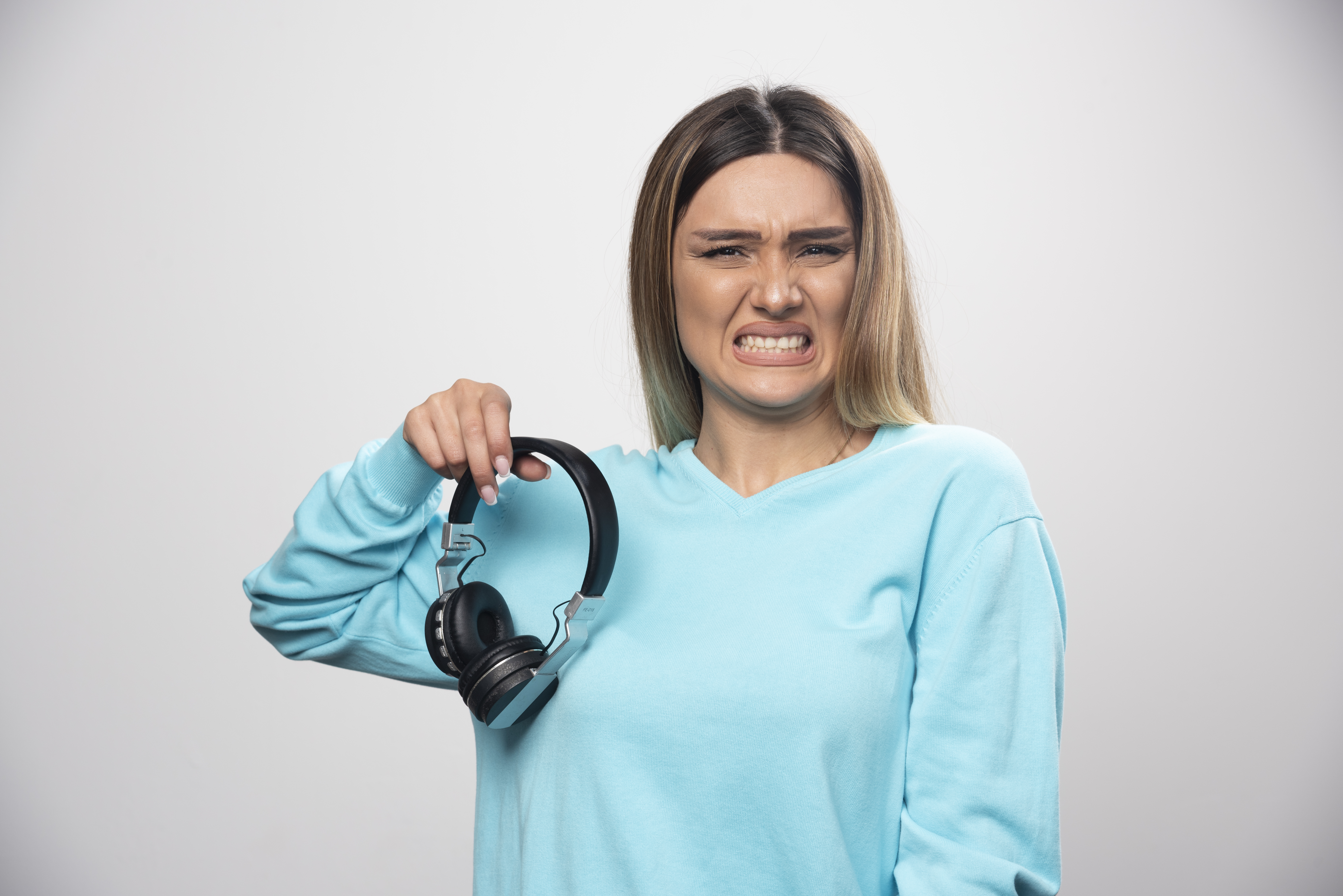 Smiling woman holding off headphones — taking a break from background noise and enjoying silence