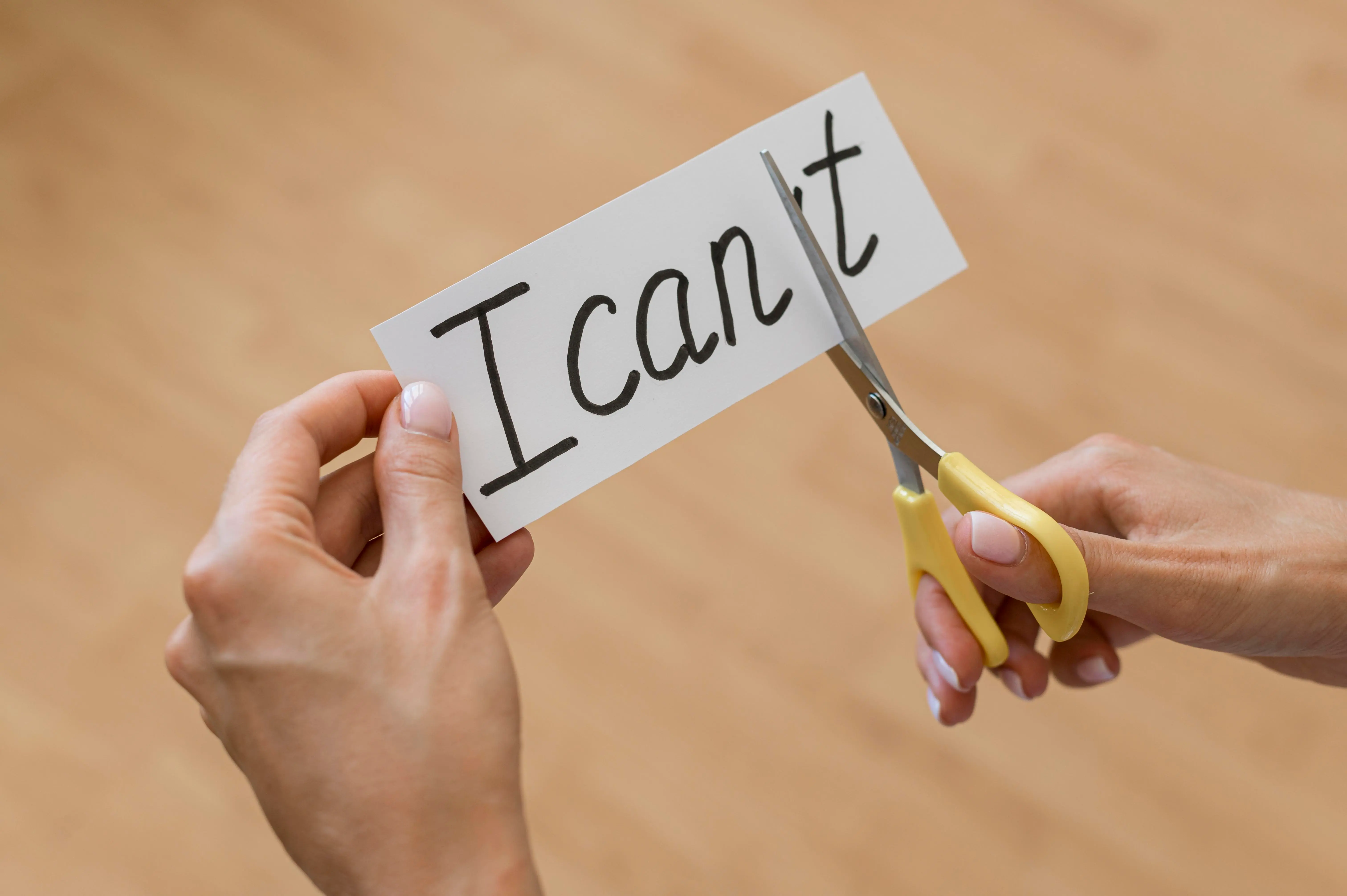 Hands cutting the word “I can’t” to reveal “I can” — symbol of overcoming self-doubt and starting late with confidence