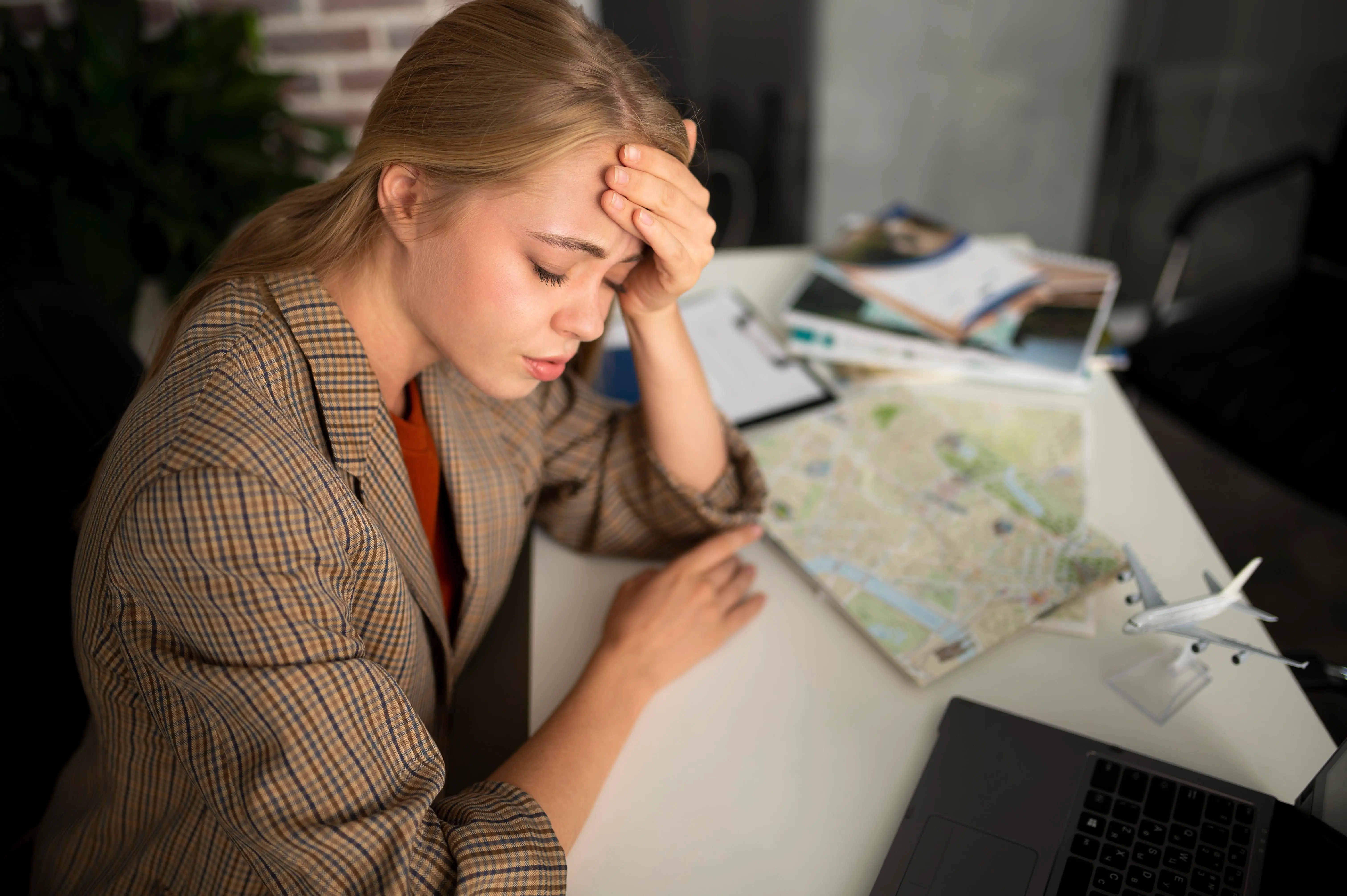 Tired female traveler planning her trip over a map at a desk
