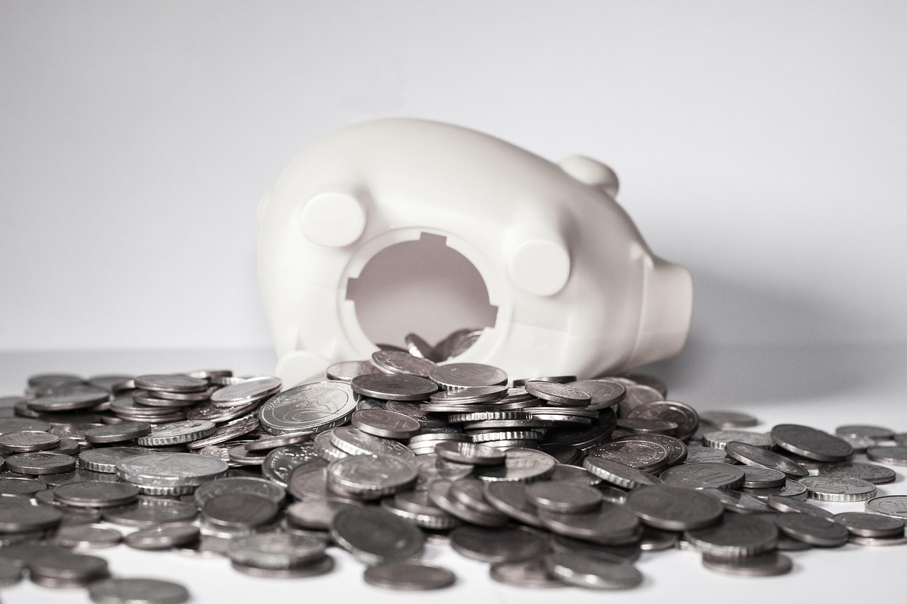 Broken piggy bank with scattered coins, symbolizing financial crisis, savings depletion, or budgeting challenges