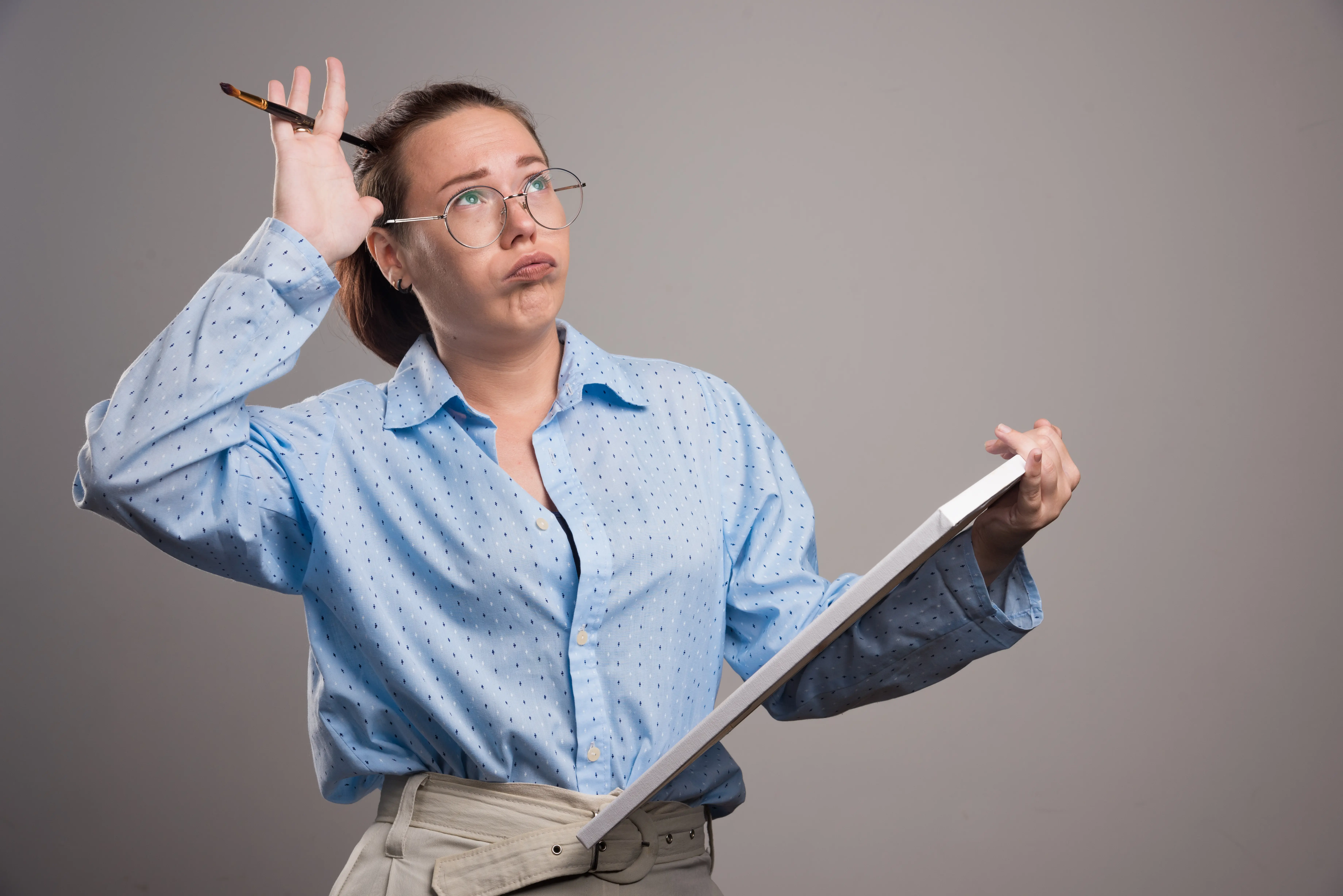 Frustrated woman struggling to concentrate while holding notepad — concept of creative block and mental overload