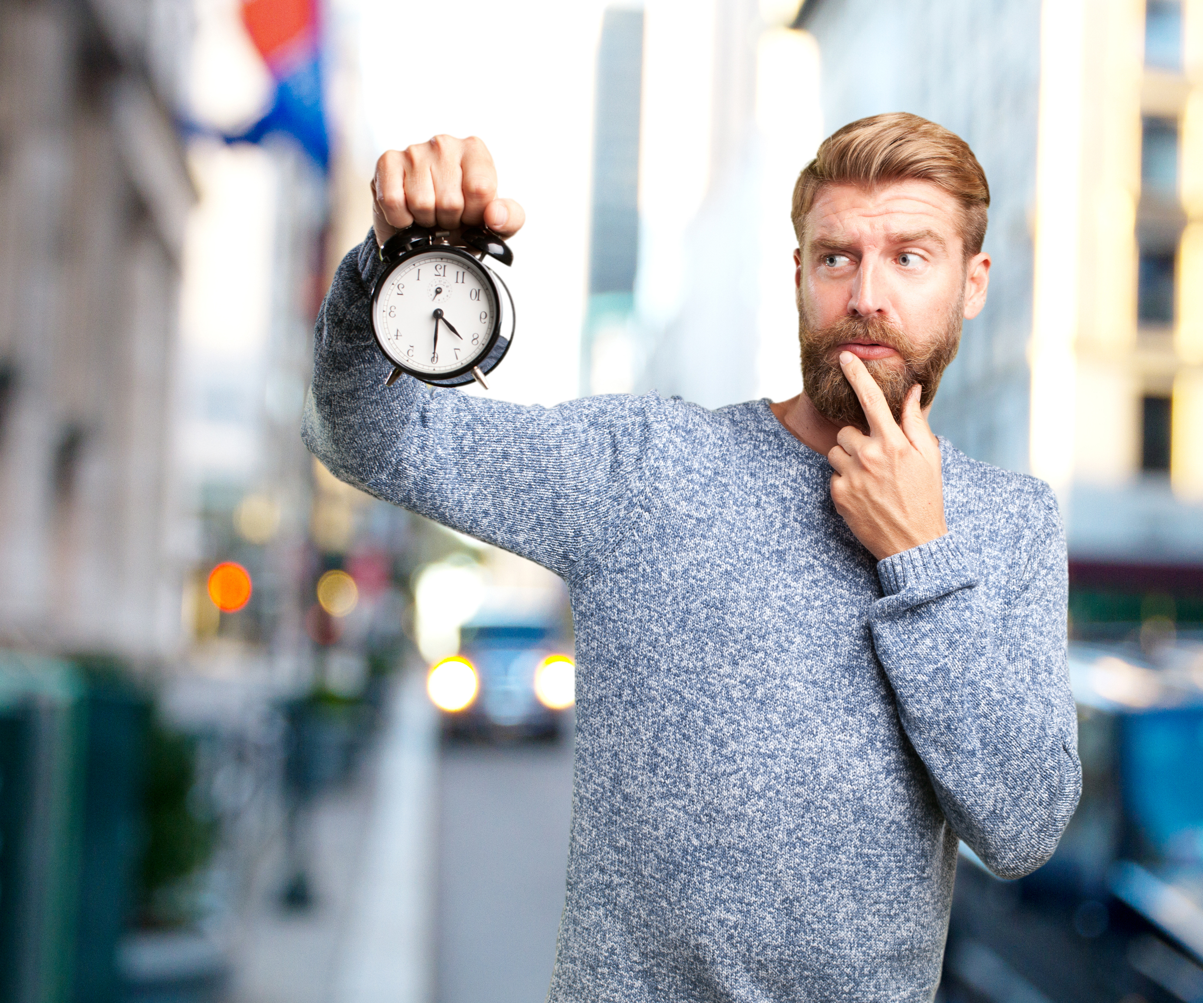 Worried young man holding a clock — symbolizing fear of starting too late in life or finances